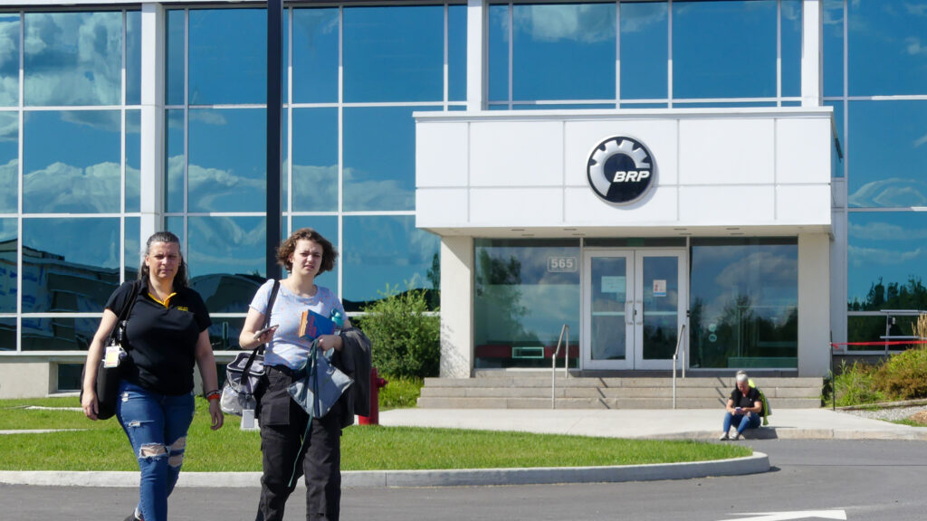 Deux employées de BRP circulent devant les installations de l'entreprise à Valcourt.